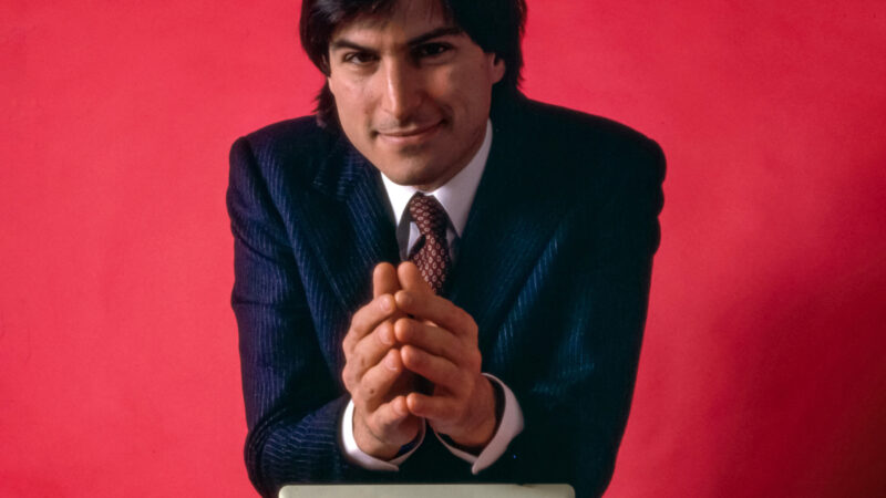 Steve Jobs sprijinit de un computer Macintosh, în ianuarie 1984